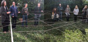 Menschen stehen auf einer Frühlingswiese und halten ein Netz 